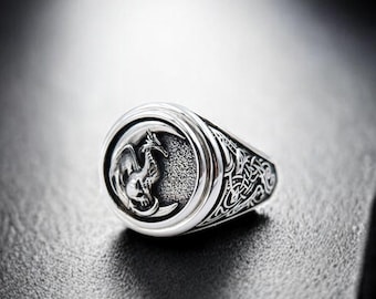May include: A silver ring with a detailed dragon design on the face of the ring.