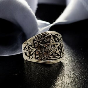 Könnte beinhalten: Ein goldener Ring mit einem detaillierten Design, das einen fünfzackigen Stern mit komplizierten Symbolen und Schriftzügen zeigt.