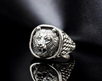 May include: A silver ring with a bear head design. The ring is on a black background.