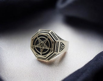 May include: A gold ring with a black pentagram design and a Celtic knot on the band.