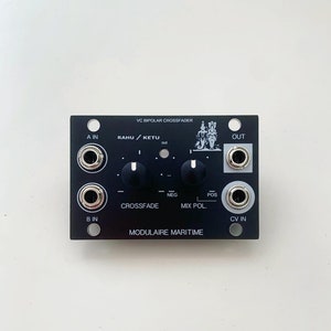 Può includere: Modulo di sintetizzatore modulare nero con jack di ingresso/uscita argentati e manopole di controllo. Il modulo presenta il testo "VC Bipolar Crossfader" e "Modulaire Maritime". Il testo aggiuntivo include "A IN", "B IN", "OUT" e "CV IN".