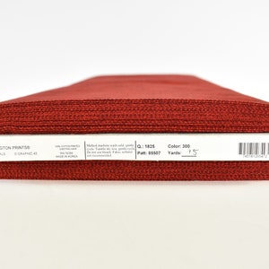May include: A roll of red fabric labeled "Wilmington Prints" Essentials, with the details "Color: 300", "Yards: 1.5", "Patt: 85507", and "MQ: 1825".