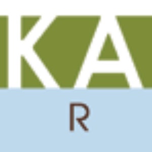 May include: A logo for Robert Kaufman Fabrics, featuring the company name in brown and green lettering with the word "Fabrics" in brown lettering below.