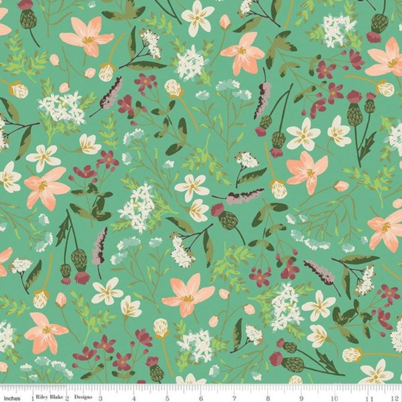 May include: A teal fabric with a repeating pattern of white, pink, and green flowers. The fabric has a ruler printed on the bottom edge.
