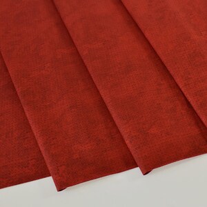 May include: Red fabric with a textured surface. The fabric is folded in a few places, showing the texture and color.