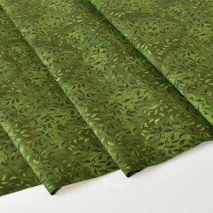 May include: Green fabric with a repeating pattern of small leaves. The fabric is folded in thirds.