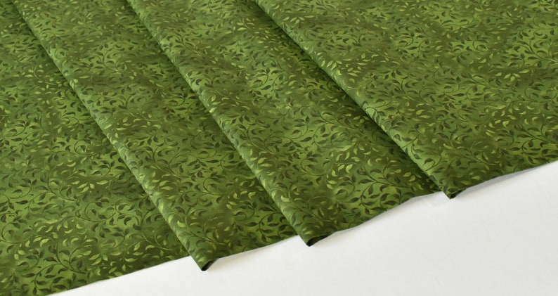May include: Green fabric with a repeating pattern of small leaves. The fabric is folded in thirds.