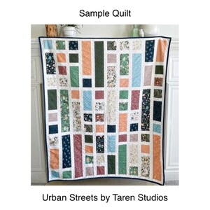 May include: A sample quilt with a geometric pattern in shades of green, blue, orange, and red. The quilt is made up of rectangular blocks with different floral patterns. The quilt is labeled "Urban Streets by Taren Studios".