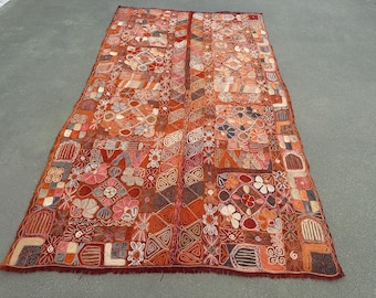 May include: A rectangular textile wall hanging featuring a vibrant orange and red base color palette. The surface is densely covered with intricate, multi-colored embroidered geometric patterns, floral motifs, and various abstract shapes.
