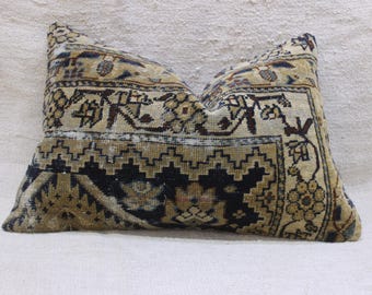 May include: Rectangular pillow with a vintage rug design. The pillow features a beige background with intricate patterns in black, brown, and blue. The design includes geometric shapes and floral motifs, creating a classic, aged aesthetic.