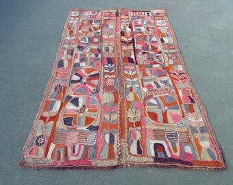 May include: A rectangular textile wall hanging featuring a vibrant, multi-colored geometric pattern. The design includes repeating circular motifs, vertical floral-like columns, and abstract shapes in shades of red, orange, pink, and purple.