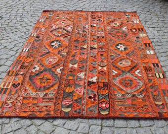 May include: A large, intricately patterned rug with a predominantly orange and red color scheme. The rug features geometric designs and a central medallion.