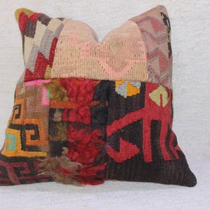 May include: A colourful patchwork cushion featuring a variety of geometric patterns and textures. The cushion is made from woven fabric and has a fringe detail.