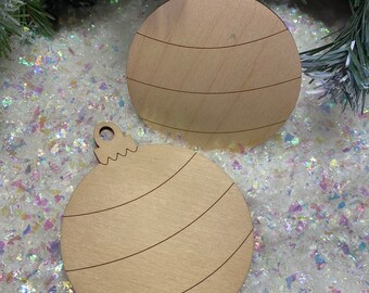 May include: Two flat, circular wooden ornaments with a light tan finish. Each ornament features a small loop at the top for hanging and is etched with three distinct, curved horizontal lines across the surface, creating a simple, layered design.