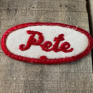 Etiquetas de identificación bordadas vintage usadas por Pete, ovaladas, rojas con parche blanco.