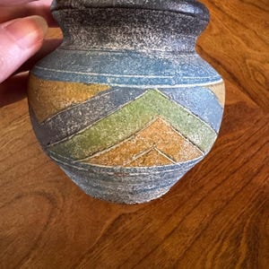 May include: A set of three ceramic mugs with a speckled, matte finish. The mugs are in shades of cream, light gray, and dark gray. Each mug has a simple, minimalist design and a rounded handle.