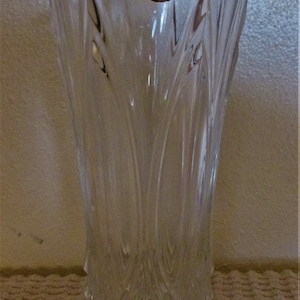 May include: A clear glass vase with a faceted design. The vase has a label that reads "Cristal d'Arques France".
