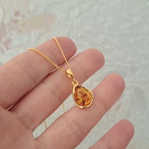 K&ouml;nnte beinhalten: Eine goldene Kettenkette mit einem tropfenf&ouml;rmigen Bernsteinanh&auml;nger.