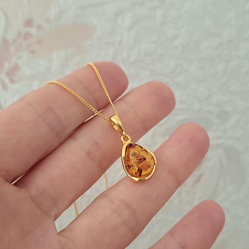K&ouml;nnte beinhalten: Eine goldene Kettenkette mit einem tropfenf&ouml;rmigen Bernsteinanh&auml;nger.