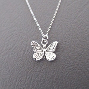 Peut inclure: Un collier en chaîne argent avec un pendentif délicat en forme de papillon. Le papillon est détaillé avec des ailes et un corps complexes.