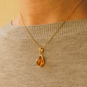 K&ouml;nnte beinhalten: Eine goldene Kettenkette mit einem tropfenf&ouml;rmigen Bernsteinanh&auml;nger.