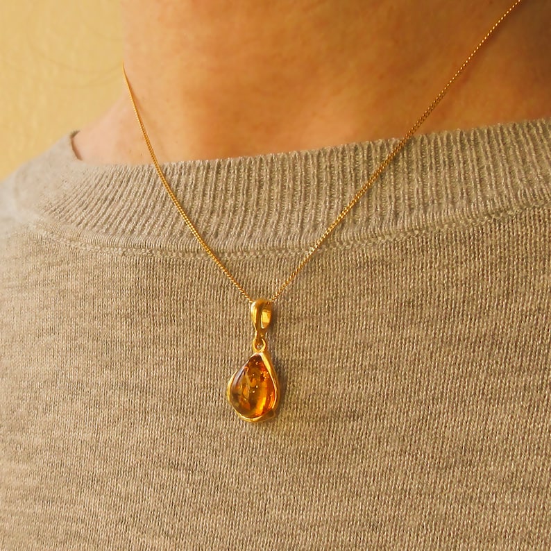 K&ouml;nnte beinhalten: Eine goldene Kettenkette mit einem tropfenf&ouml;rmigen Bernsteinanh&auml;nger.