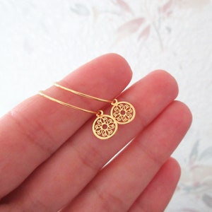 Peut inclure: Une paire de boucles d'oreilles créoles en or avec de délicats pendentifs circulaires en filigrane.