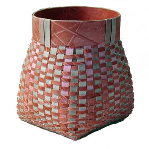 May include: A woven basket with a square base and a rounded top. The basket is made of strips of paper in shades of pink, red, and grey. The top rim of the basket is a solid red.