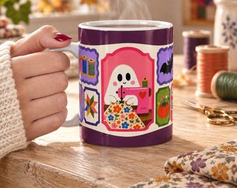 May include: A purple ceramic mug featuring a central illustration of a white ghost using a pink sewing machine to stitch a floral fabric. The design includes smaller rectangular frames displaying spools of thread, a quilt block, a bat, and a pumpkin.