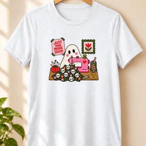 White t-shirt with the "Just One More Seam" folk-art ghost sewing print, laid flat. Color: White.