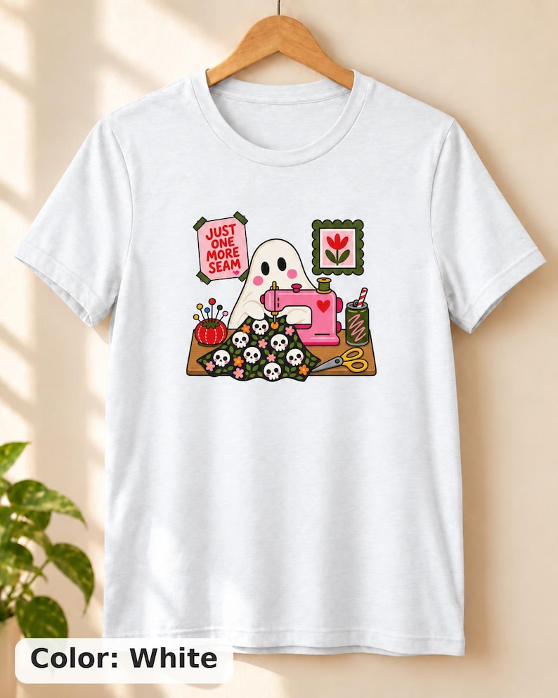 White t-shirt with the "Just One More Seam" folk-art ghost sewing print, laid flat. Color: White.