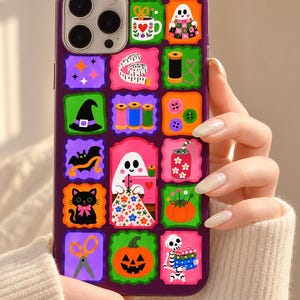 Könnte beinhalten: Eine violette Smartphone-Hülle mit einem Raster aus bunten quadratischen Symbolen mit Halloween- und Näh-Motiven, darunter ein Geist, eine schwarze Katze, ein Kürbis, ein Skelett, eine Schere, Garnrollen und ein Maßband.