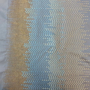 May include: A close-up of a fabric with a gradient pattern of blue and gold squares. The fabric has a textured, woven look.