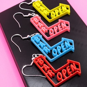 May include: Four pairs of earrings with silver hooks. Each earring features a colourful arrow with the words "Bar Open" in white lettering.