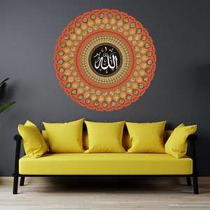 Pode incluir: Um sofá amarelo com três almofadas fica em frente a uma parede cinza com um grande adesivo de parede de mandala laranja e dourado que apresenta a palavra árabe "Allah" no centro.