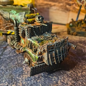 May include: A detailed model of a post-apocalyptic truck, featuring a weathered, battle-worn aesthetic. The truck is painted in shades of green, brown, and yellow, with visible rust and damage. It has a chain across the front and a machine gun on the side.