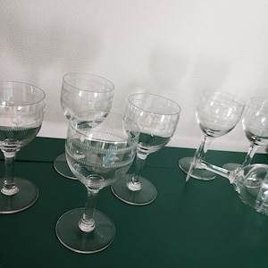 Peut inclure: Ensemble de six verres à vin en verre transparent avec un motif gravé. Les verres ont un bol rond et une longue tige.