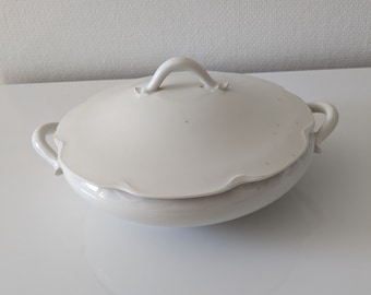 May include: White porcelain serving dish with a lid and two handles. The dish has a scalloped edge and a simple design.