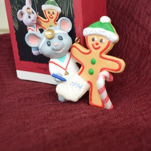 May include: A vintage 1994 Hallmark Keepsake Ornament featuring a gray mouse doctor with a stethoscope and a blue pen, examining a gingerbread man wearing a green Santa hat and holding a candy cane.