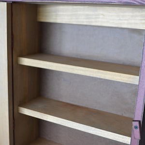 Puede incluir: Un armario de madera con una sola puerta y tres estantes. El armario est&aacute; pintado de un color marr&oacute;n claro con un ribete marr&oacute;n m&aacute;s oscuro. La puerta est&aacute; cerrada y los estantes est&aacute;n vac&iacute;os.