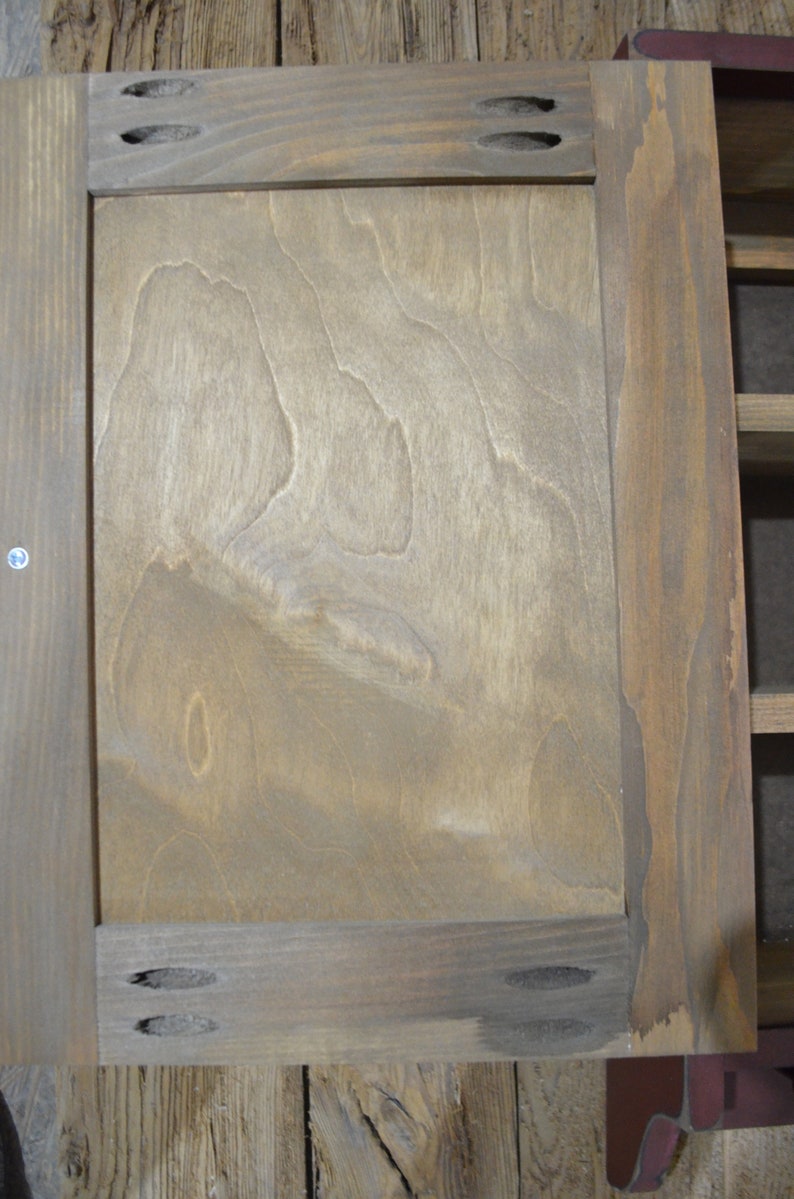Puede incluir: Una puerta de armario de madera con un acabado de grano de madera marr&oacute;n claro. La puerta tiene un dise&ntilde;o simple con un marco y un solo panel. La puerta est&aacute; cerrada y tiene algunos peque&ntilde;os agujeros en el marco.