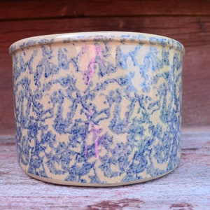 May include: A white ceramic crock with a blue and white floral pattern. The crock is round and has a wide mouth.