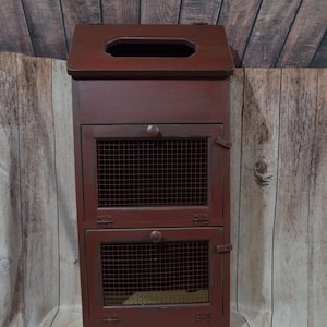 May include: A red wooden cabinet with two wire mesh doors and a hinged top. The cabinet has a distressed finish and is perfect for storing kitchen items.