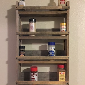 May include: A rustic wooden spice rack with five shelves, holding various spices and seasonings in glass jars and bottles. The jars and bottles include McCormick, Lawry's, and Valspar brands.