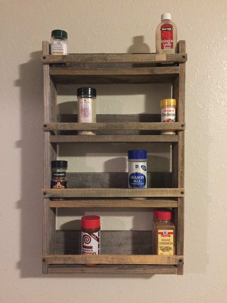 May include: A rustic wooden spice rack with five shelves, holding various spices and seasonings in glass jars and bottles. The jars and bottles include McCormick, Lawry's, and Valspar brands.