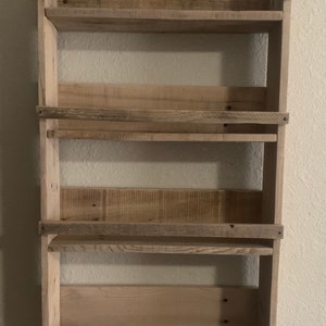 May include: A rustic wooden shelf unit with four shelves. The shelves are made of reclaimed wood and have a natural, weathered finish.