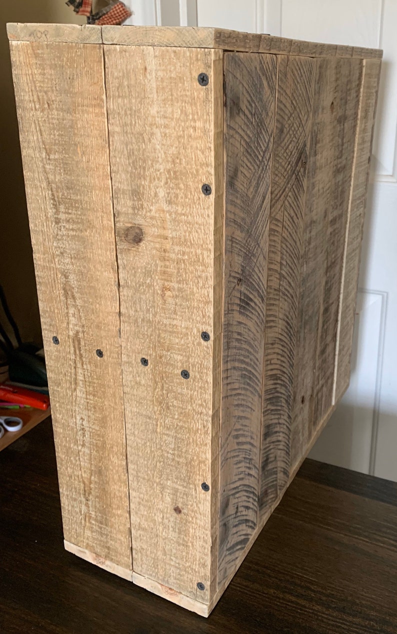 May include: A rustic wooden cabinet made from reclaimed wood. The cabinet has a natural wood colour and features a single door and a shelf. It is ideal for storing small items or displaying decorative objects.