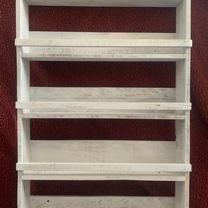 May include: White wooden wall mounted shelf unit with five shelves. The shelves have a distressed white finish and are perfect for displaying small items.