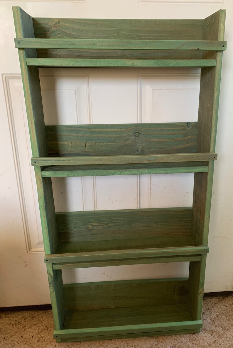 May include: A green wooden shelf unit with four shelves. The shelves are made of rustic wood and have a distressed finish.