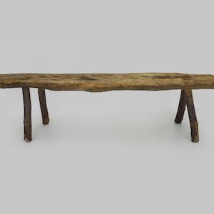 Peut inclure: Banc en bois rustique à l'aspect naturel et vieilli. Le banc a une assise rectangulaire et trois paires de pieds robustes en branches brun foncé. Le bois est brun clair avec des veines et des nœuds visibles.